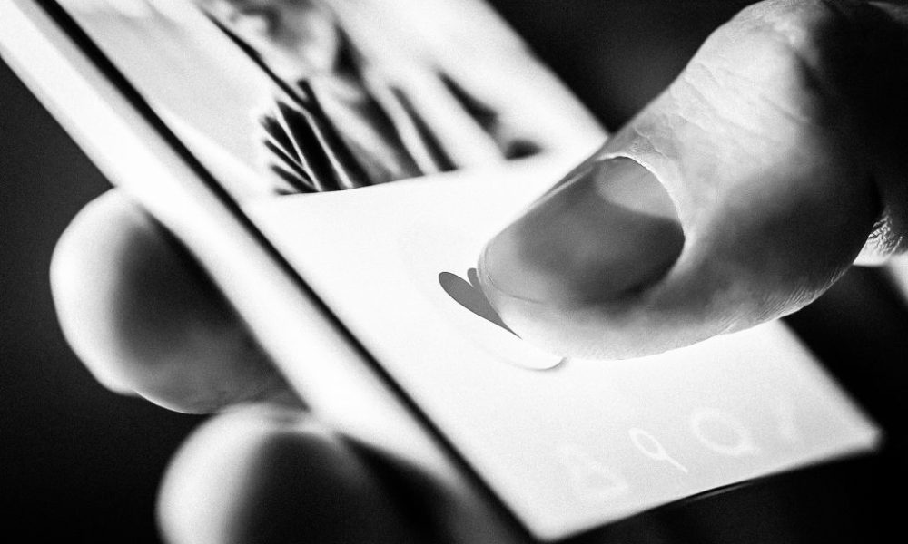 close up shot of a hand holding a smartphone with dating app displayed on the screen